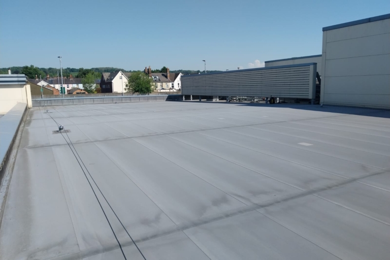 Grey single-ply membrane on a large flat commercial roof in Surrey.