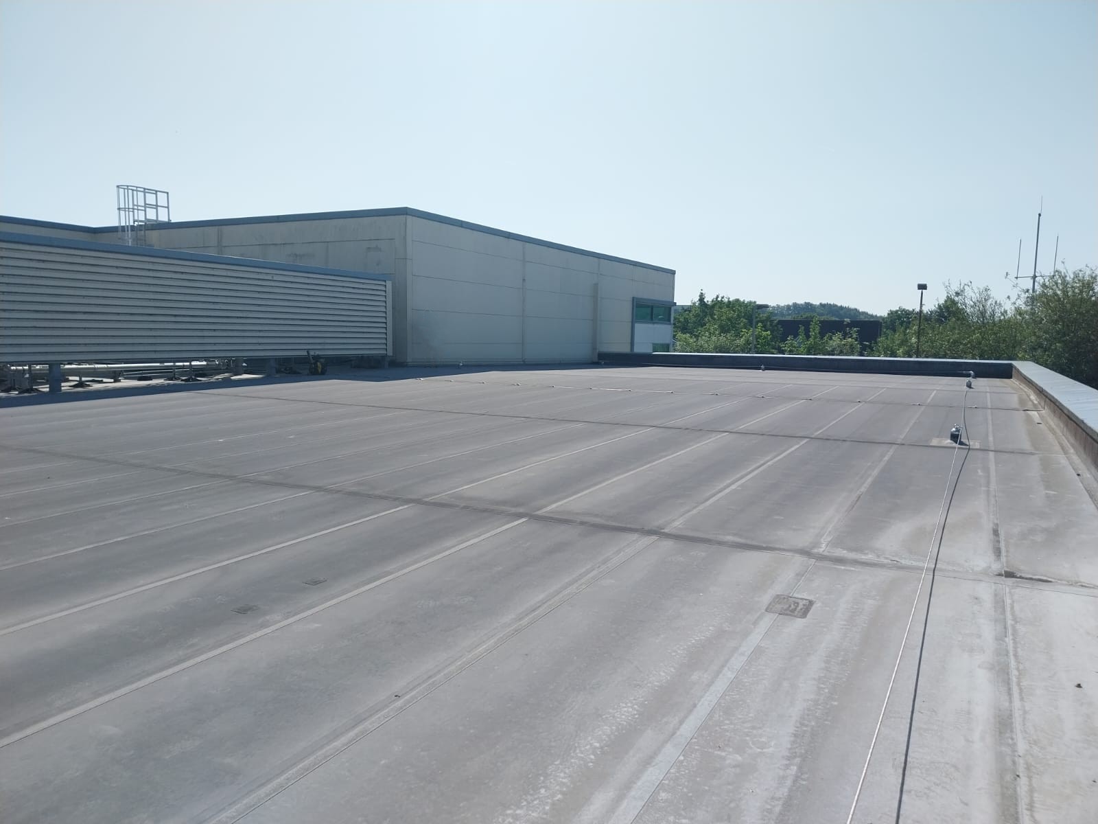 Large flat commercial roof with electronic leak detection equipment in Surrey.