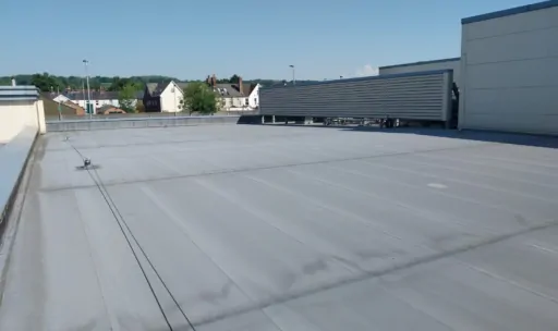 Grey single-ply membrane on a large flat commercial roof in Surrey.