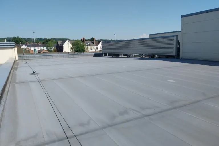 Grey single-ply membrane on a large flat commercial roof in Surrey.